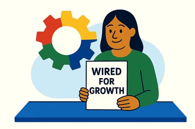 A woman sits at a blue table holding a document titled “Wired for Growth.” Behind her, a large, fully colored MyHardWired gear in the correct orientation is displayed on the wall. A soft blue abstract shape frames the background, and the scene reflects clarity, confidence, and alignment.